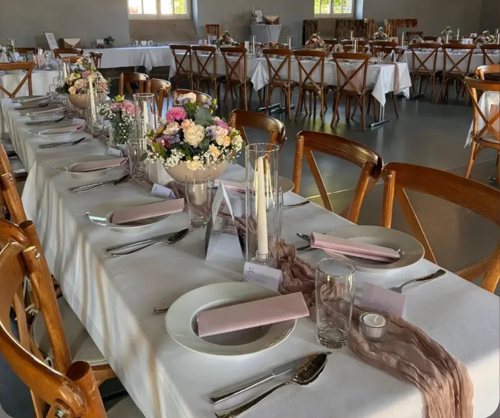 Lange Hochzeitstafel mit weißer Tischwäsche und rosa Servietten