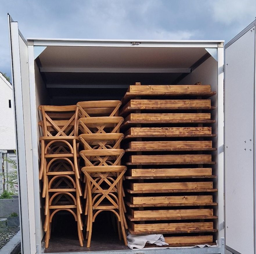 Mietanhänger beladen mit Holztischen und Crossback-Stühlen